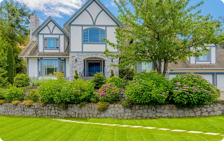 Striped front lawn and shrub border outside a Tudor-style home for Airbnb lawn care in Vancouver