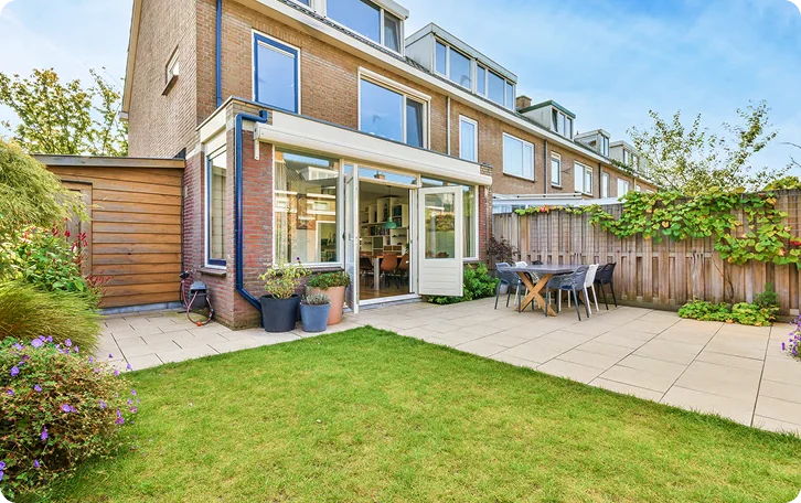 Townhouse backyard with a stone patio and trimmed lawn for retirement home lawn care in Vancouver