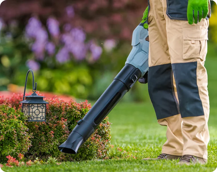 Worker using a leaf blower by flower beds for absentee landlord lawn care in Vancouver